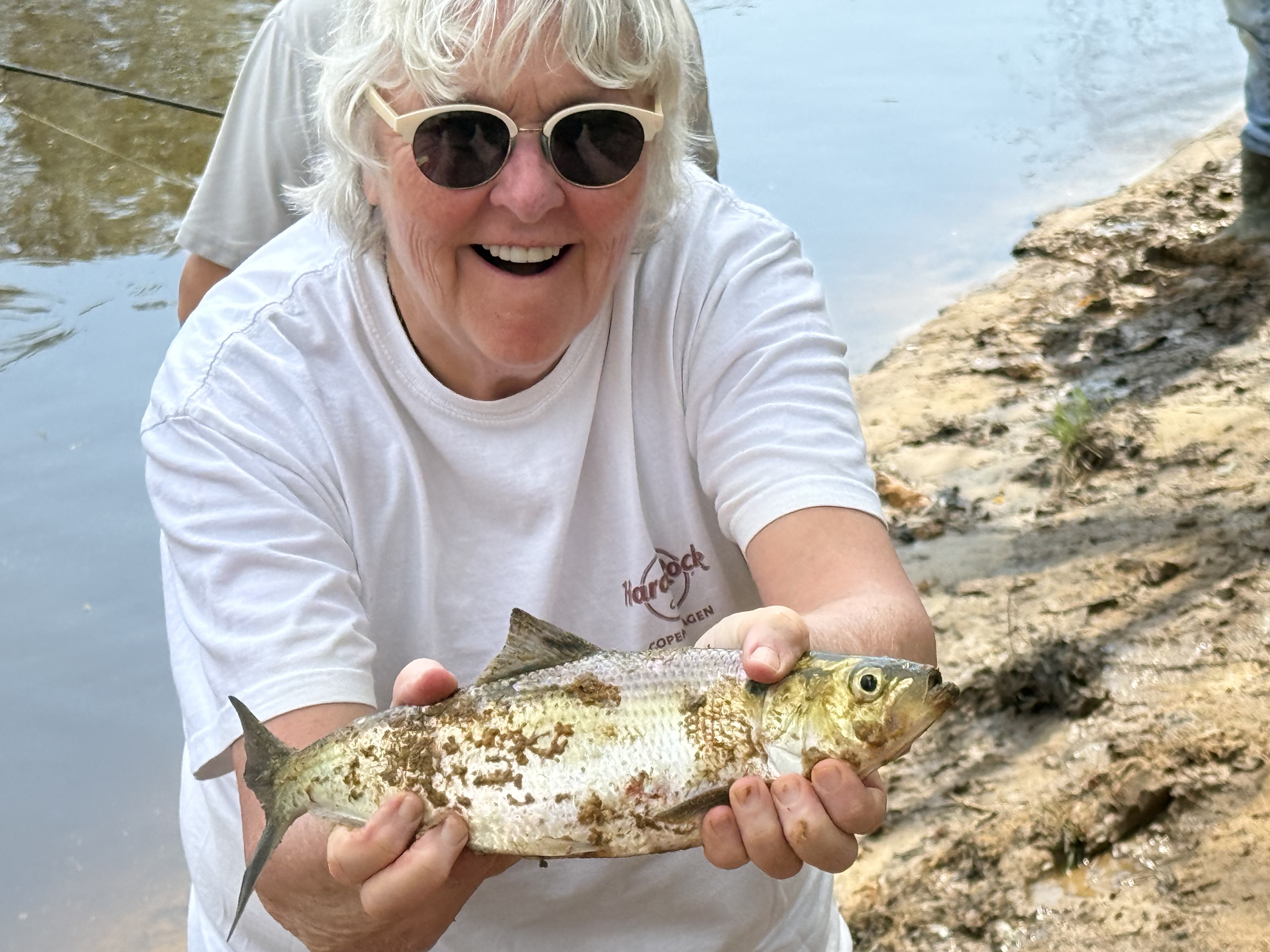 Man posing with girl on the beach with a fish.