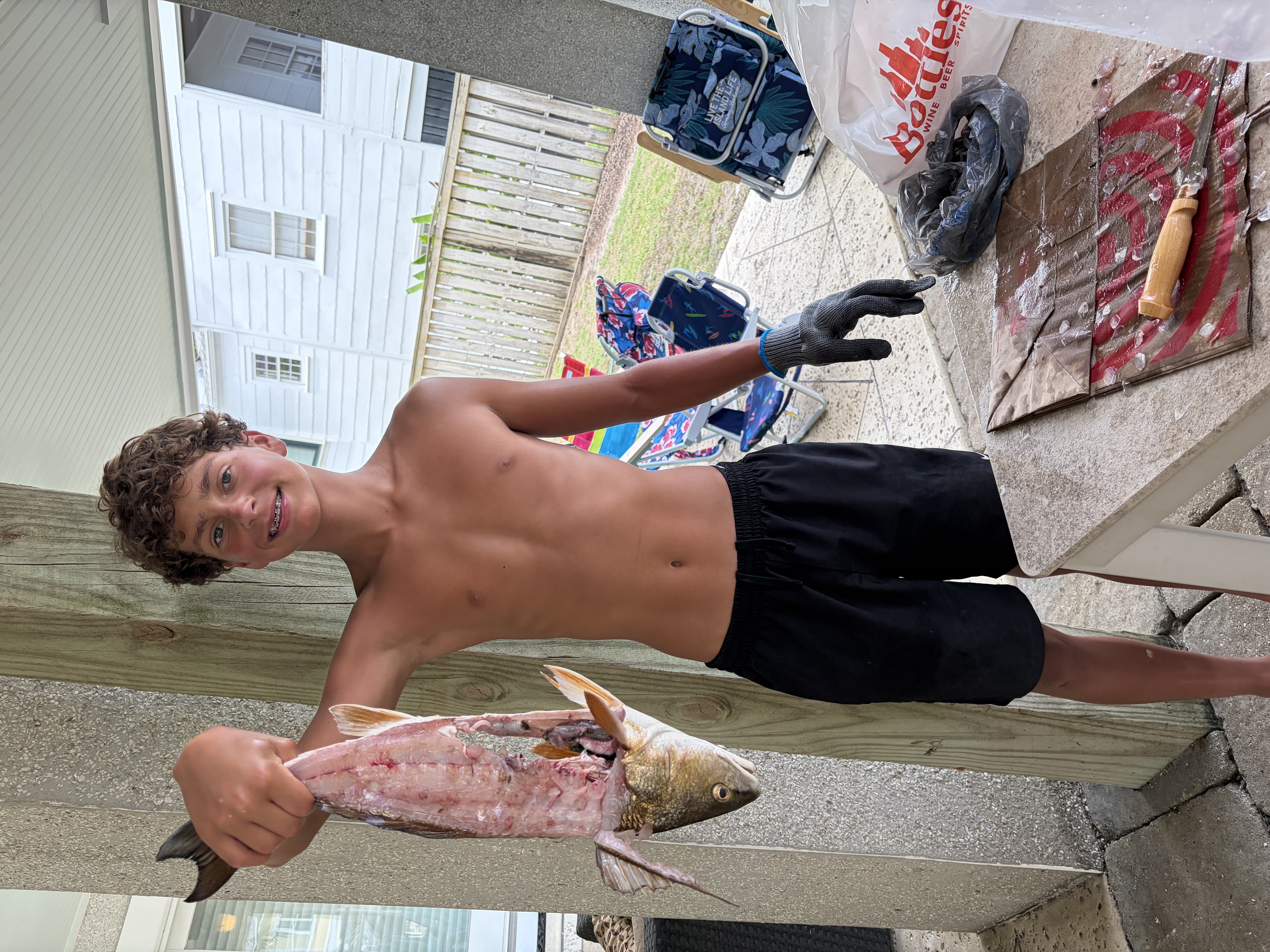 Man posing with girl on the beach with a fish.