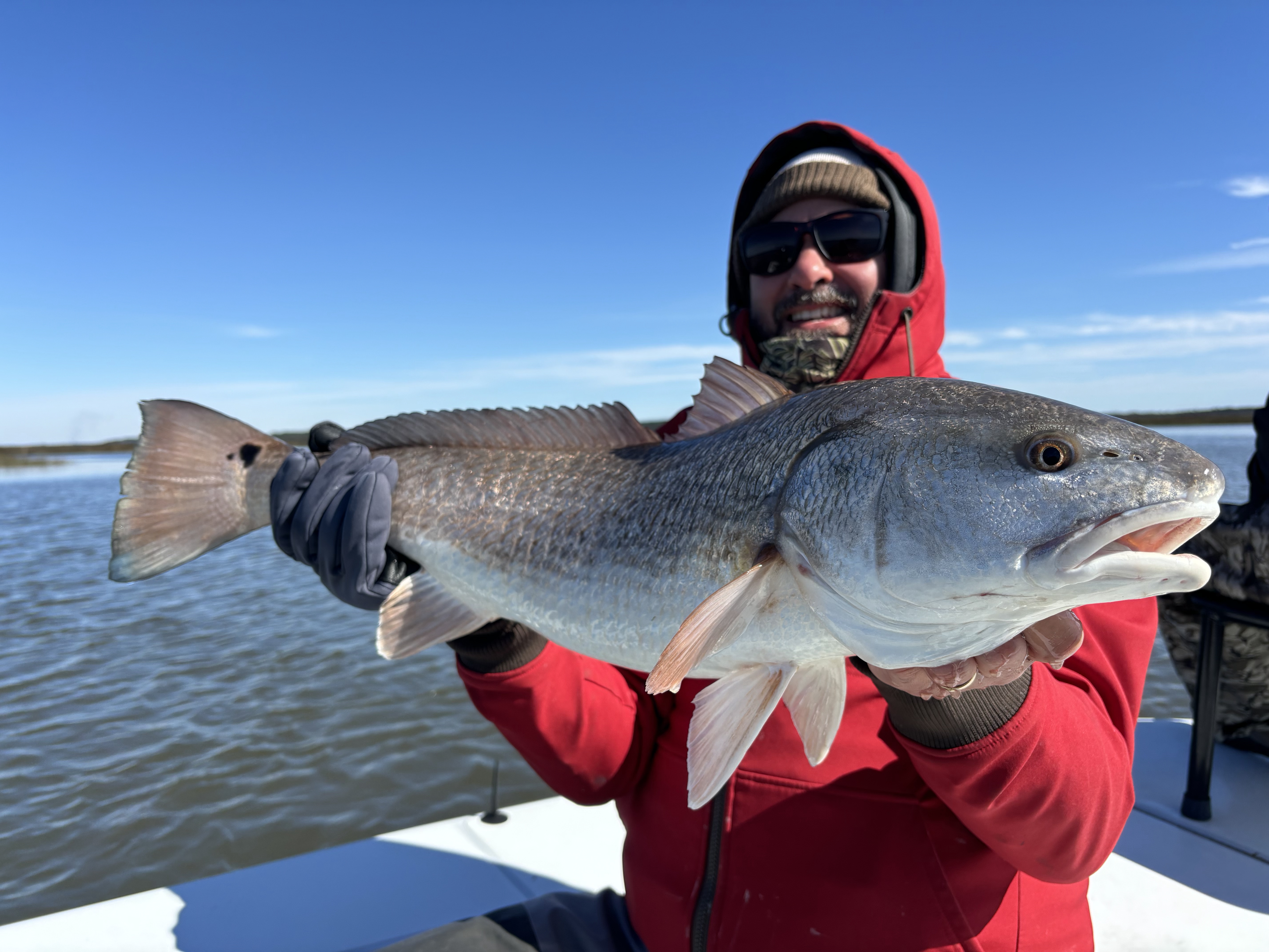 Man posing with girl on the beach with a fish.
